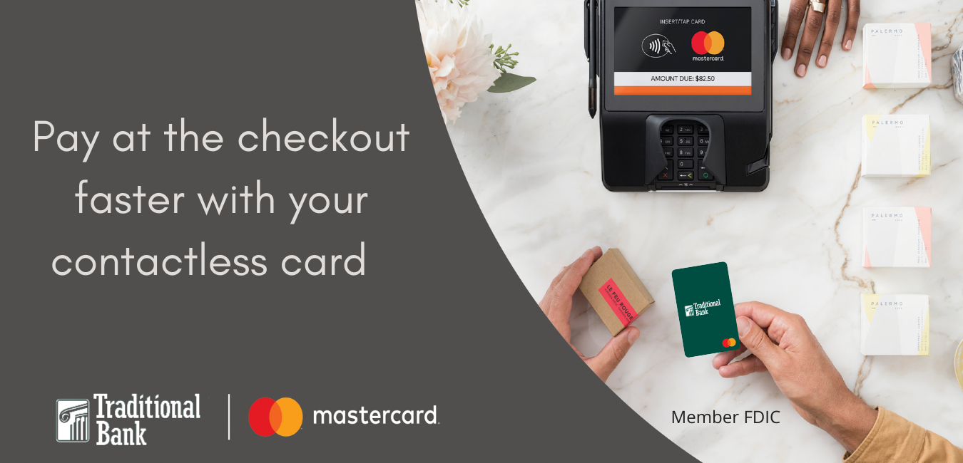 Hand holding a Traditional Bank debit card at the payment counter ready to use a card reader