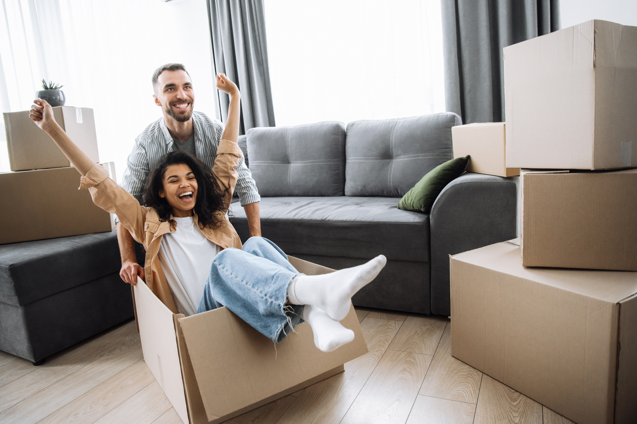 girl sitting in box happy with her hands up while guy pushes box 