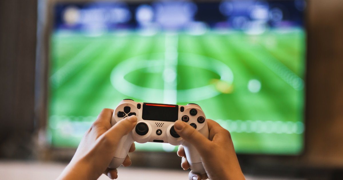 hands holding up gaming controller in front of tv