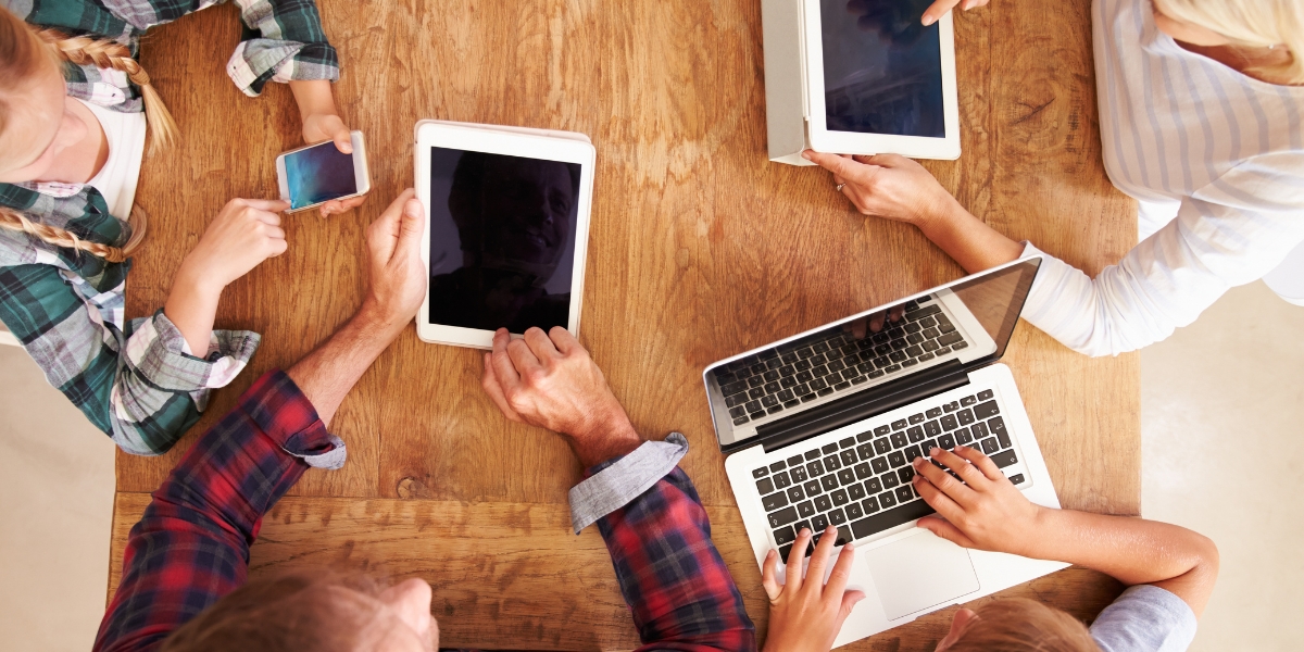 kids and adults at the table with ipads and laptops