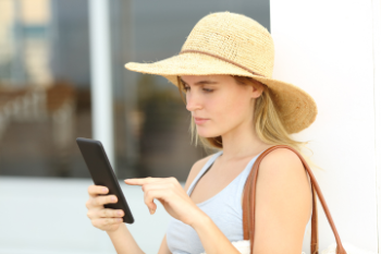 woman with sun hat looking at phone and tapping it  Banner