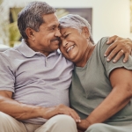 older black couple hugging and laughing on couch 