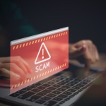 hands on laptop with scam alert in red